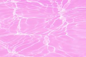 Defocus blurred transparent pink colored clear calm water surface texture with splashes and bubbles. Trendy abstract nature background. Water waves in sunlight with copy space. Pink water shining. photo