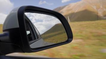 vista desde el interior de un automóvil que conduce a lo largo de la carretera hasta el espejo lateral durante la lluvia. el concepto de vehículos y conductores. nadie. video