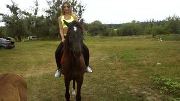 la jeune femme mince monte des chevaux sur l'herbe près du poulain video