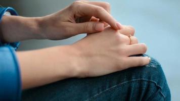 a young girl is sitting with folded hands and moves her fingers across the skin close up video