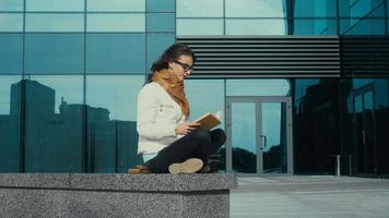 bello giovane brunetta donna lettura un' libro nel il strada video