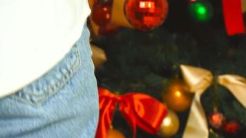 encantadora joven decora un árbol de navidad con una bola roja brillante en casa en 4k video