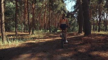 belleza joven conduciendo una bicicleta en el bosque