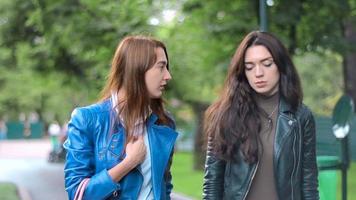 two girlfriends in leather jackets slowly go down the street and talk to close up video