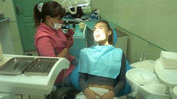 junges charmantes mädchen behandelt ihre zähne von einem zahnarzt