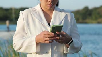 milieu ingenieur vervelend een wit helm toepassingen een mobiel telefoon naar Vermelding gegevens analyseren zuurstof niveaus in een reservoir. water en ecologie concept. video