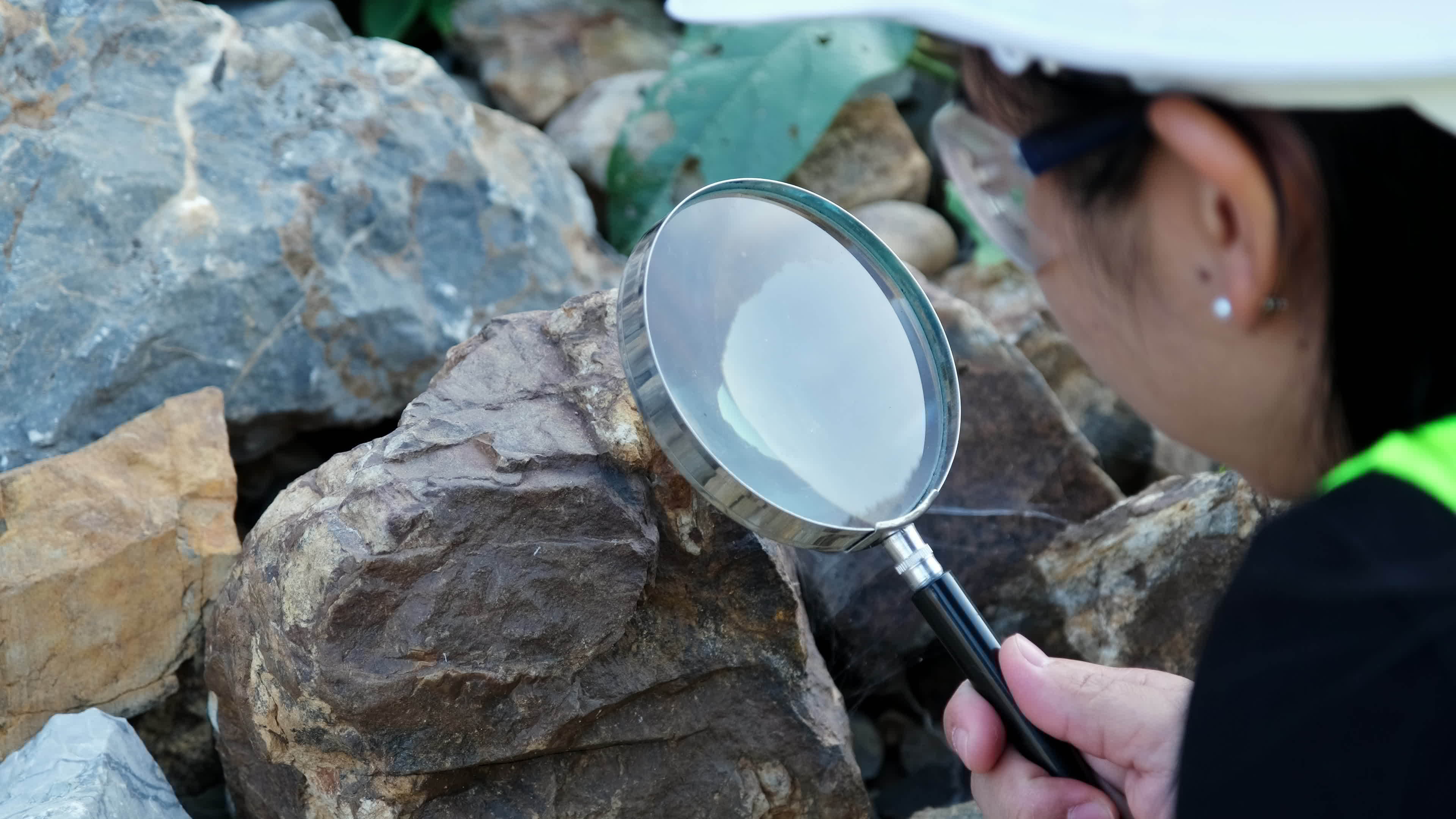 Female geologist using a magnifying glass examines nature analyzing Female geologist using a magnifying glass examines nature analyzing