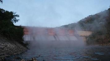 cenário da manhã na represa de kiew lom, lampang, tailândia. barragem hidrelétrica, comporta com água fluindo pelo portão. barragem com central hidroeléctrica e rega. video