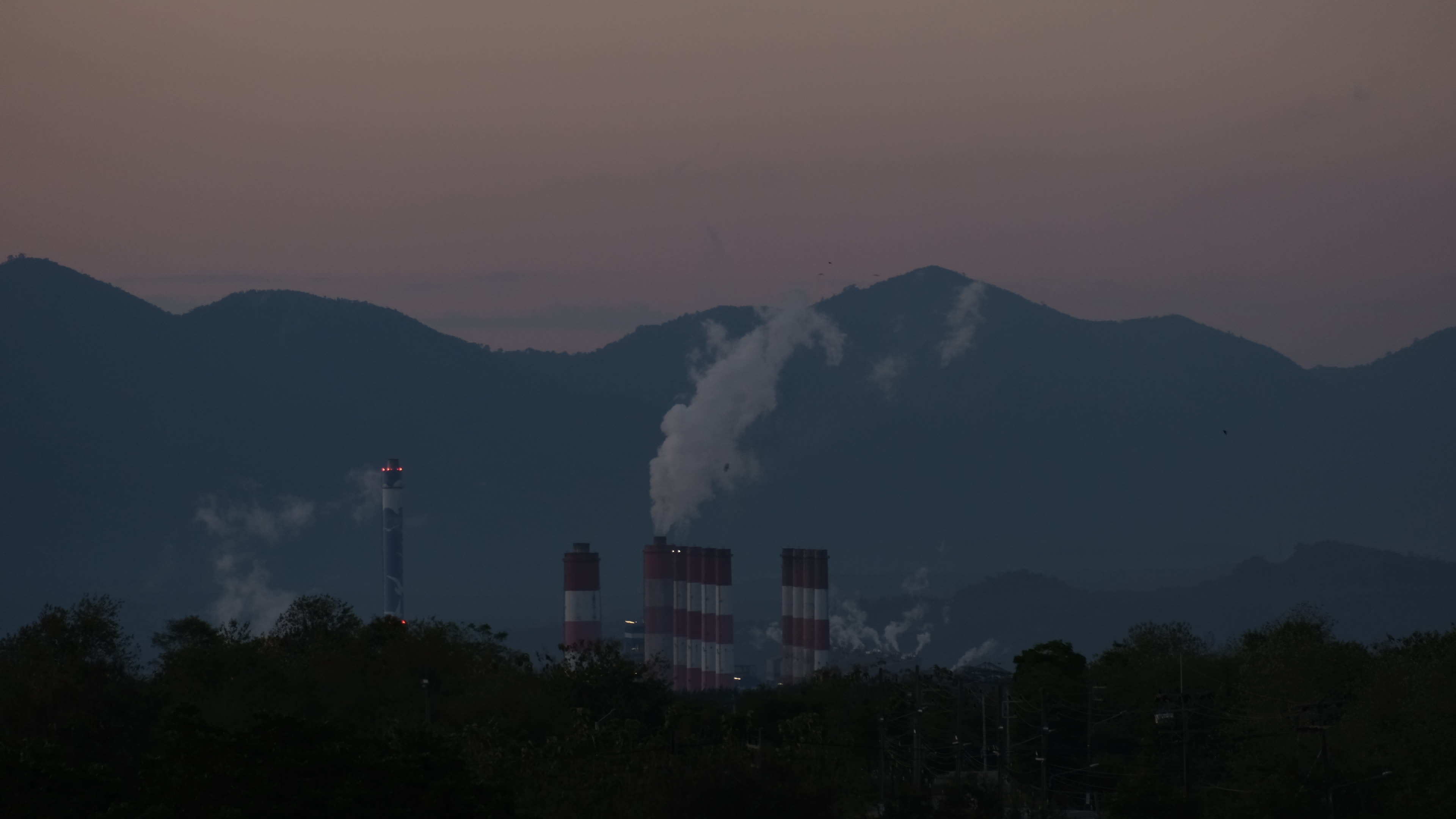 Coal power plant with steam pouring out of stacks during sunset