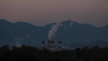 steenkool macht fabriek met stoom- gieten uit van stapels gedurende zonsondergang. industrieel rook stack van steenkool macht fabriek in de avond. milieu vervuiling. fabriek pijp vervuilend lucht. video