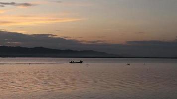 Silhouette of fishermen enjoying a beautiful sunset in their boat while fishing video