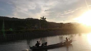 silueta de pescadores disfrutando de una hermosa puesta de sol en su bote mientras pescan