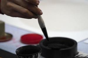 japanese woman writing ideograms with brush photo