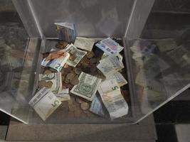 dollars euro and coins inside transparent tip box photo