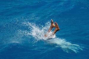 maldivian man diving from boat in blue ocean photo