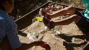 süßes kleines Mädchen, das als kleine Archäologin spielt, während ihre Mutter auf dem Spielplatz nach Dinosaurierfossilien gräbt. Kinder lernen etwas über die Simulation von Dinosaurierfossilien im Park. video