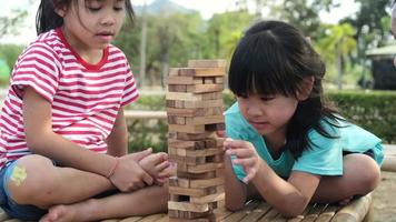 Excited kids and mom playing Jenga tower wooden block game together in the park. Happy family with children enjoying weekend activities together. video