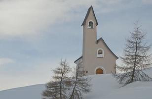 A small mountain church in snow background winter time photo