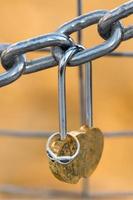 Love padlock and engagement ring hanging from a chain photo