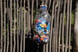 Bottles cups to recycle. Big plastic gallon full of colored bottles cups sunny day. photo