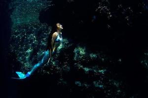 sirena nadando bajo el agua en el océano azul profundo foto