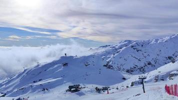 vista de inverno das montanhas com nuvens abaixo na estância de esqui. atividades e esportes de inverno. estilo de vida aventureiro. casa da montanha ao fundo. video