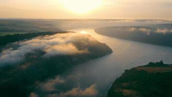 Morgen Sommerlandschaft. Luftaufnahme aus einer Höhe der Sonnenaufgangslandschaft über dem Fluss. Nebel über dem Fluss und orangefarbene Sonne, die den Nebel beleuchtet. Entspannung und Meditation. video