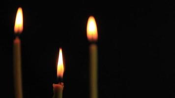 un primer plano de una vela encendida con llama amarilla, una luz de vela en la oscuridad, se quema y después de un rato una ráfaga de viento la apaga. video