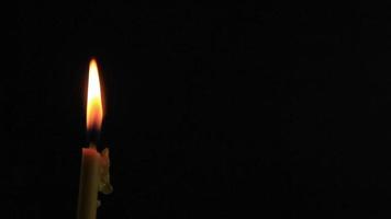 un' avvicinamento di illuminazione candela con giallo fiamma, un' leggero di candela nel il scuro, esso ustioni e dopo un' mentre un' raffica di vento si spegne esso. video