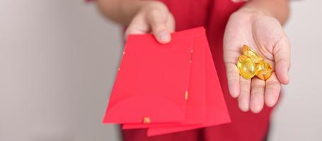 Woman holding Chinese red envelope with gold bullion, money gift for happy Lunar New Year holiday. Chinese sentence means happiness, healthy, Lucky and Wealthy photo
