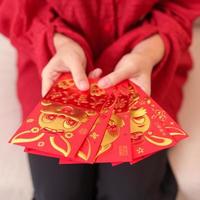 woman holding Chinese red envelope with golden rabbit and blessing word, money gift for happy Lunar New Year holiday. Chinese sentence means happiness, healthy, Lucky and Wealthy photo