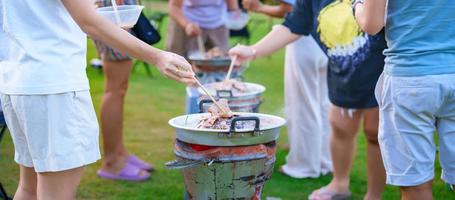 Hand grill Pork or meat with vegetables and soup on the hot pan, party of friend group and gang against nature outdoor. Traditional Thai BBQ style is famous in Thailand photo