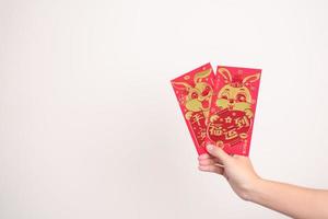 woman holding Chinese red envelope with golden rabbit and blessing word, money gift for happy Lunar New Year holiday. Chinese sentence means happiness, healthy, Lucky and Wealthy photo