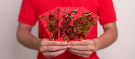 man holding Chinese red envelope with golden rabbit and blessing word, money gift for happy Lunar New Year holiday. Chinese sentence means happiness, healthy, Lucky and Wealthy photo