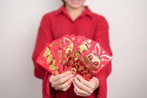 Woman holding Chinese red envelope with golden rabbit and blessing word, money gift for happy Lunar New Year holiday. Chinese sentence means happiness, healthy, Lucky and Wealthy photo