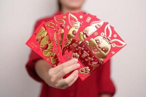 Woman holding Chinese red envelope with golden rabbit and blessing word, money gift for happy Lunar New Year holiday. Chinese sentence means happiness, healthy, Lucky and Wealthy photo