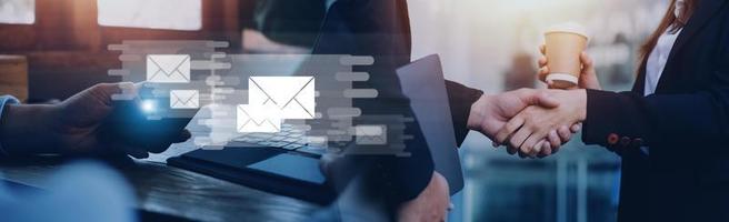 Businessman hands using Laptop typing on keyboard and surfing the internet on office table with email icon, email marketing concept, send e-mail or news letter, online working internet network. photo