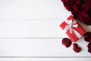 Close up red gift box with bunch of rosy roses blurred background. Valentine's day, wedding, birthday and special occasion concept. Copy space for text. photo