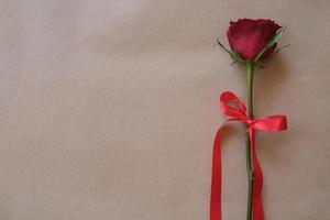 Top view of a red rose tied with red ribbon on wooden background. Valentines day concept. Copy space for text. photo