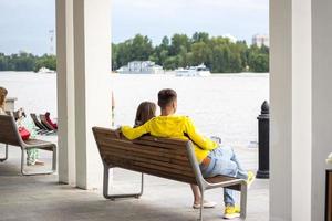 2022-07-17. Rusia. Moscú. estación fluvial del norte. jóvenes, una pareja está sentada en un banco, admirando la vista del río. otras personas están descansando cerca. foto