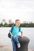 A boy in a blue T-shirt with a backpack on his back. Journey.  The face expresses natural joyful emotions. Not staged photos from nature