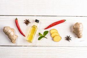 Layout of condiments with ginger and ginger oil  on light wooden background. photo