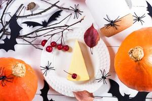 imagen de halloween calabazas, decoraciones negras como arañas, búhos, ramitas, trozo de pastel de calabaza en blanco. foto