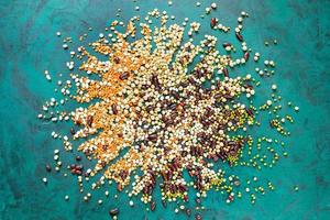 Different beans are scattered from center of emerald green background. Top view. photo