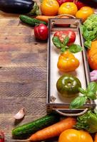 Frame of fresh farm vegetables in small box and on old rustic weathered vintage wooden table. Vertical orientation. photo