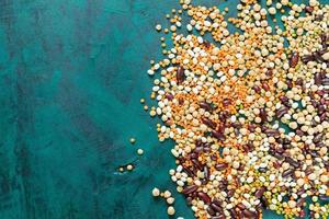 Different beans are lying on emerald green background in the right with copy space. photo