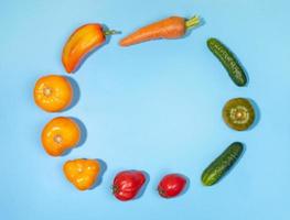 Different fresh farm vegetables laid out in circle on blue background with copy space for text in center. Top view. photo