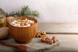 Wooden bowl with whitehomemade yogurt and nuts on burlap on wooden planks. photo