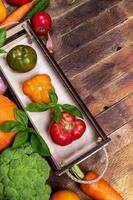pequeña caja de madera con tomates de granja frescos y maduros y verduras en una mesa rústica antigua con espacio para copiar.