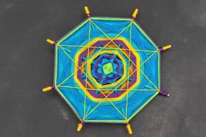 Multicolored handmade mandala on dark grey background. photo